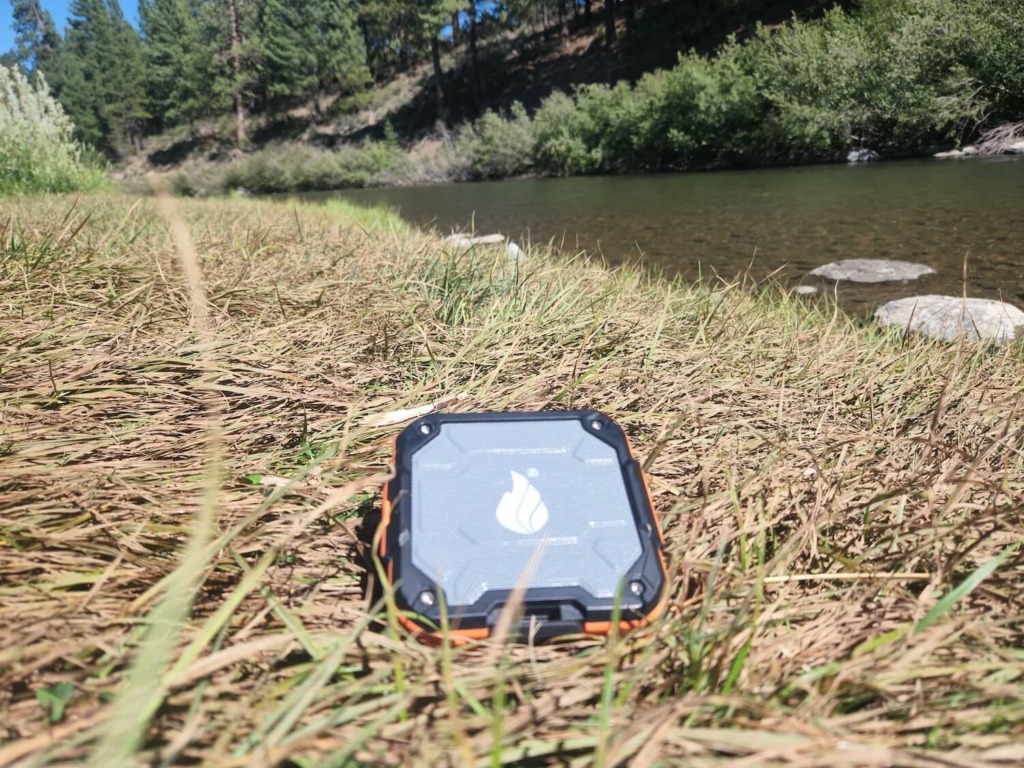 blackfire portable waterproof speaker in grass on river edge