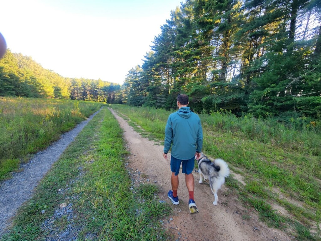 Man and dog walking in meadow wearing best ultralight windbreaker