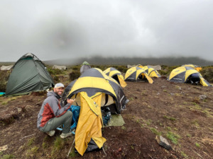 The Backpack Guide in the Tushar rain jacket outside a tent