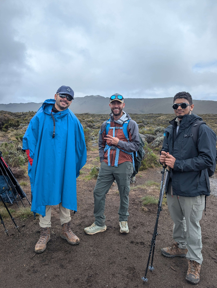 Three men on Kilimanjaro hike with the man in the middle wearing Tushar Rain jacket