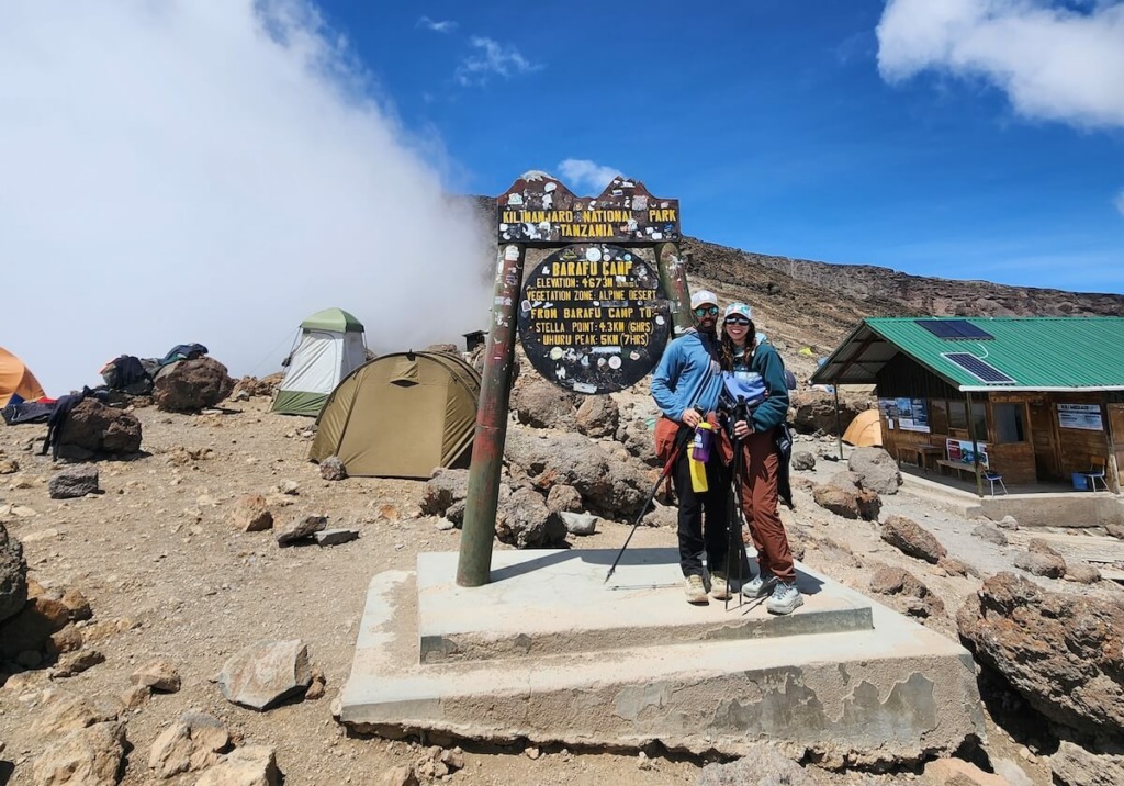 Man and woman standing at sign for Barafu Camp