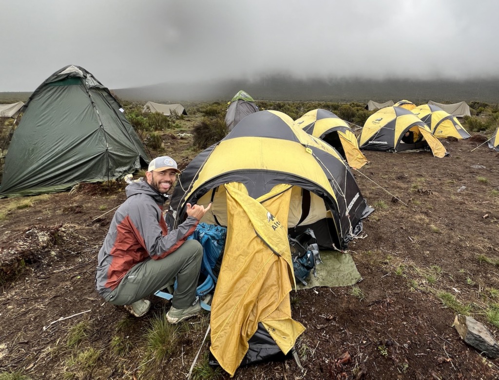Man wearing HOKA Kaha 3 GTX hiking boots entering a tent